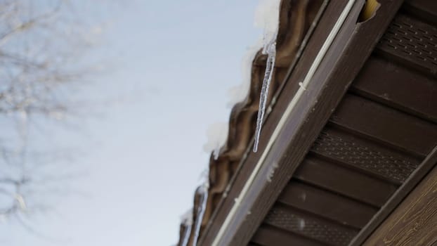 Winter roof. Action.A landscape where you can see large icicles dripping down hanging on top of the house and you can see the blue sky. High quality 4k footage