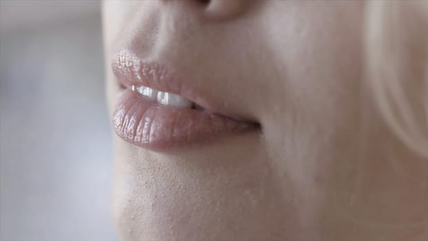 Close-up of lips of beautiful blonde woman in sunlight. Action. Body and face care.