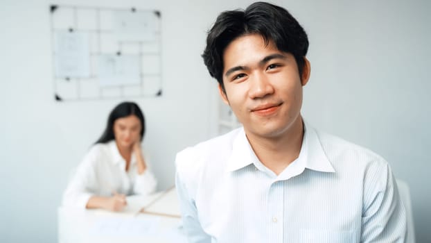 Professional happy businessman smiles during looking at camera. Young beautiful caucasian colleague drawing a blueprint on meeting table with house model and blueprint at modern office. Immaculate.