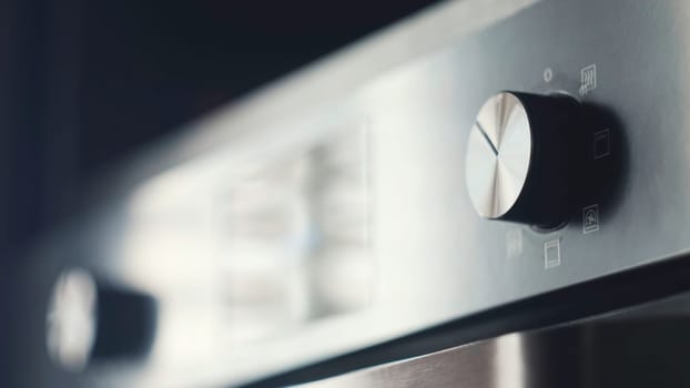 Close-up of modern plate panel. Concept. Kitchen stove handles with modern stylish design. Metal grey panel with round oven handles on stove.