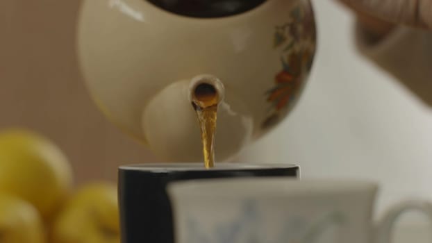 Woman's hand pour tea from teapot into the glass 4K