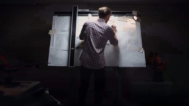 Young man drawing diagram on whiteboard. man standing in front of board with drawings. Back view of a businessman full body standing in front of a black chalkboard with hand drawn words concerning the formation process of success. Back view. draft