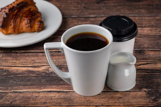 Filter coffee brewed in a white porcelain cup in a filter coffee machine, with milk and a take away glass