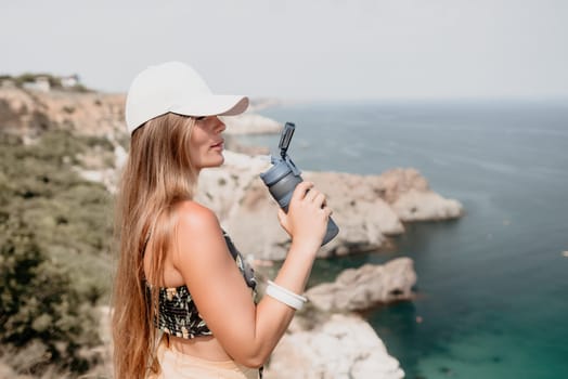 Woman travel sea. Happy tourist taking picture outdoors for memories. Woman traveler looks at the edge of the cliff on the sea bay of mountains, sharing travel adventure journey.