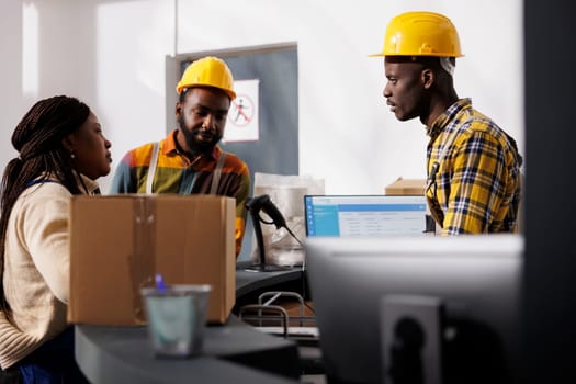 African american delivery service workers team discussing merchandise dispatching management at counter desk. All black men and woman warehouse employees register customer order parcel at reception