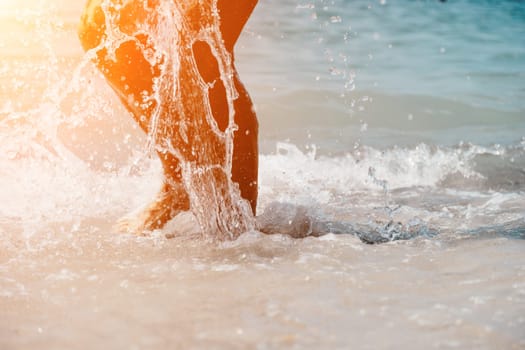 Sea beach travel - woman walking on sand beach leaving footprints in the white sand. Female legs walking along the seaside barefoot, close-up of the tanned legs of a girl coming out of the water