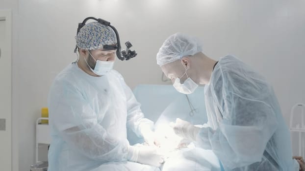 Surgeons work during operation. Action. Two professional surgeons are quietly performing operation. Two surgeons perform operation in calm environment.