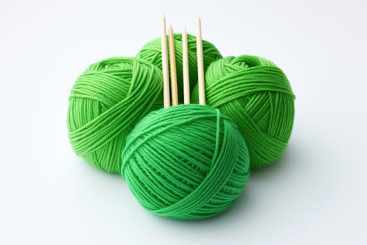 Balls of green yarn for knitting with knitting needles on a white background.