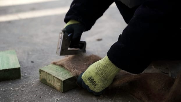 Laying the floor. Clip. A man makes a special fiber for insulation of floors in houses with a stapler