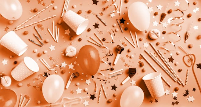 Color of the year 2024: Peach Fuzz.Birthday party background. Balloons, candles, confetti, candies and party supplies on blue, top view flat lay banner