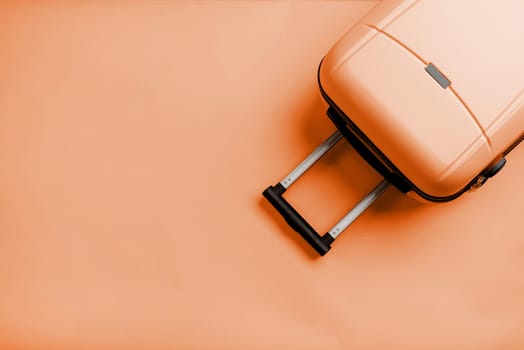 Color of the year 2024: Peach Fuzz. travel plan, trip and vacation, minimal. Top view travel bag or suitcase on solid background