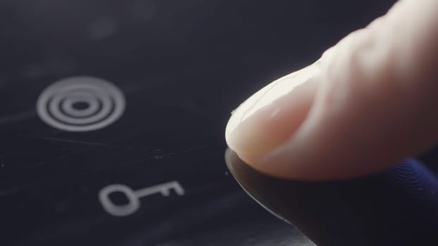 Person using touch controls on a modern glass topped hob to switch on an electric hotplate. Action. Close up of turning on the induction hob