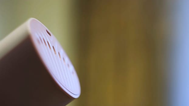 Close up of hand steamer for ironing clothes. Small pink electronic device for ironing with water steam on blurred background.
