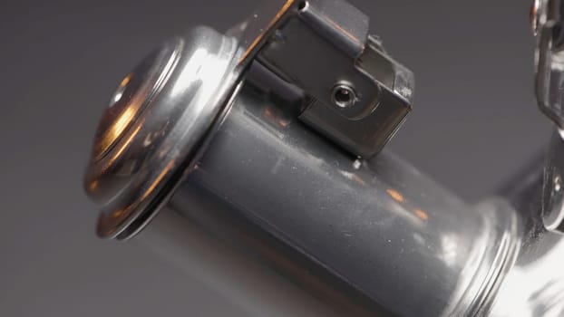 Close up of spinning closed short spout of a metal silver kettle on blurred grey wall background. Action. Spinning new teapot