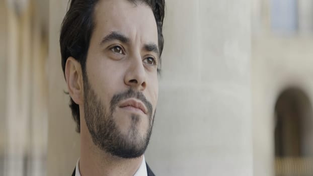 Portrait of a man with black hair and stubble. Action. A man in a black suit and a bow tie around his neck who poses for the camera. High quality 4k footage