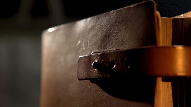 Old leather book with a strap. Close up of an ancient leather brown diary or book with yellow pages isolated on black background.
