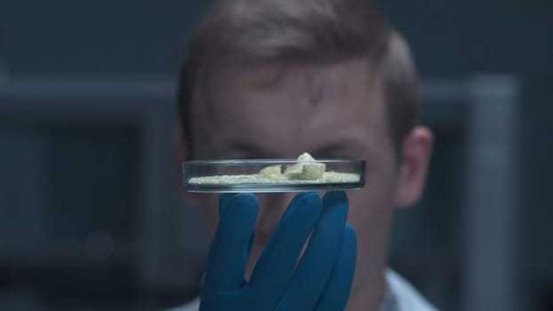A scientist holding a Petri Dish with Virus and bacteria cells. A medical or agricultural scientist, chemist or researcher holding a petri dish with clear fluid. Petri dish with sample.