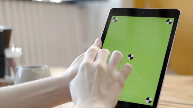 Man working with tablet tapping on green screen. Stock footage. Close-up of smooth hands holding and pressing on touch green screen of tablet.