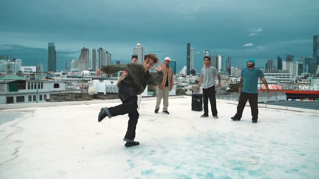 Hispanic hipster dancing surrounded by multicultural friend at city view with blue sky. Group of street dancer performing at rooftop. Active, fun, happy atmosphere. Outdoor sport 2024. Endeavor.