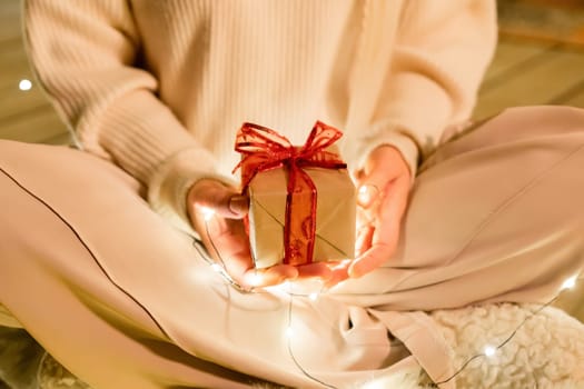 gift woman hands. Close up shot of female hands holding a small gift wrapped with red ribbon. Small gift in the hands of a woman