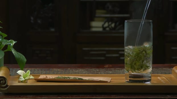 The tea ceremony. The woman pours hot water into the teapot with tea. Glass teapot with blooming tea flower inside 4K