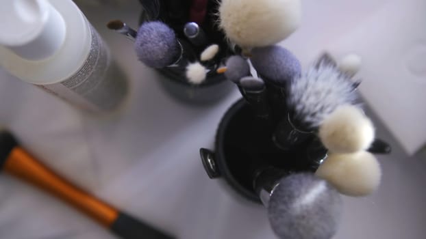 Close up of set of make up tools on white table background. Top view of many different brushes for make up in glasses, beauty industry concept.