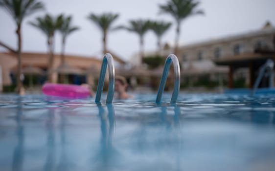 Wet metal handrails on surface of pool. . Summer vacation and lifestyle concept.