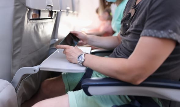 Man hands with a smartphone sits in cabin of airplane or train. Travel app concept