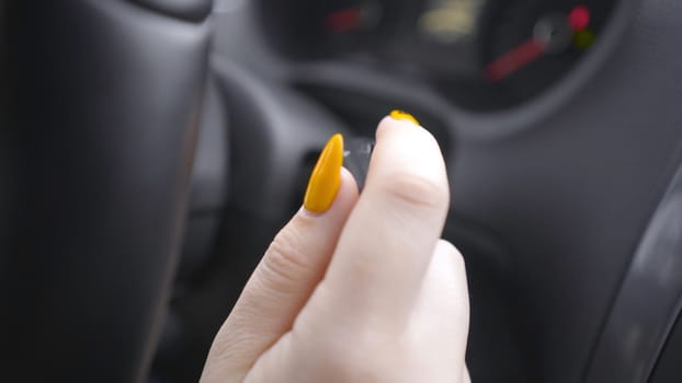 Close-up of woman switching turn signals. Action. Woman with manicure switches turn signal lever or turns on wipers. Woman behind the wheel of car.