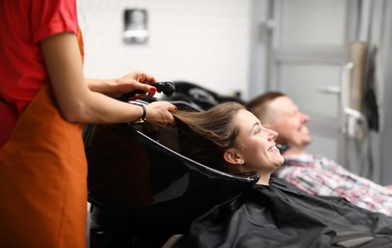 Beautiful happy smiling woman, professional hairdresser washes hair. Charming woman preparing her hair for new haircut concept