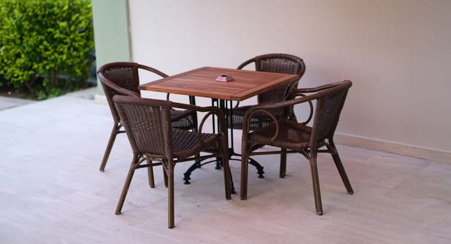 Wooden table with chairs standing on summer terrace. Outdoor furniture concept