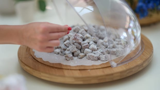 Woman hand taking piece of Turkish delight with coconut closeup. Turkish sweets concept
