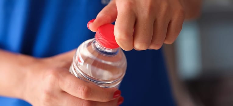Female hands opening plastic water bottle closeup. Drinking regimen concept