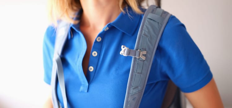 Backpack hanging on shoulders of woman in blue t-shirt closeup. Comfortable travel concept