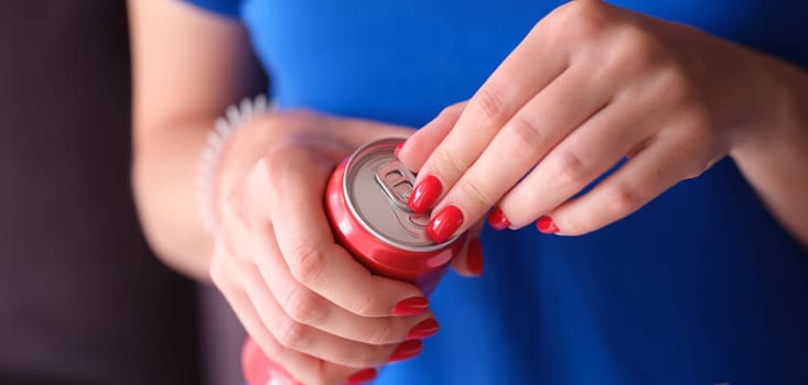 Woman with red manicure opening iron can with drink closeup. Soft carbonated drinks concept