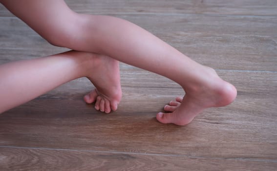 Bare feet of child standing on wooden floor closeup. Healthy lifestyle hardening concept