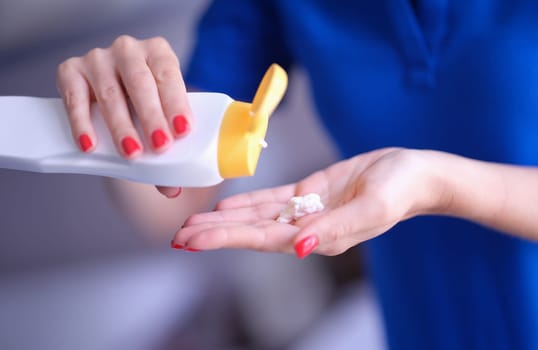 Woman pouring moisturizing body lotion from bottle on hand closeup. Skin care concept