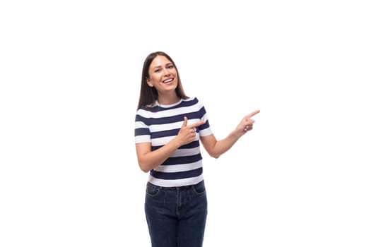 a slender young brunette caucasian woman with light make-up dressed in a striped t-shirt and jeans points with her hands to an empty space.