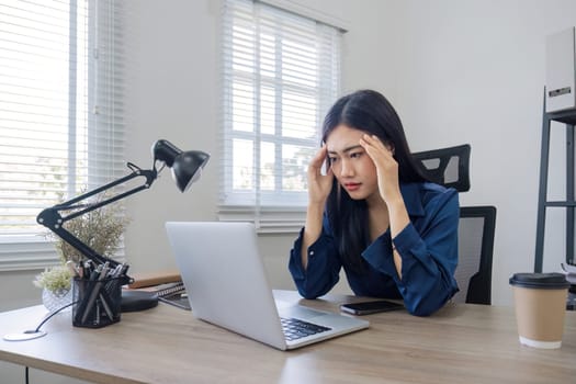 Young Asian business woman is having trouble controlling her online work in front of a laptop screen. Serious Asian businesswoman worried about solving work problems on computer.