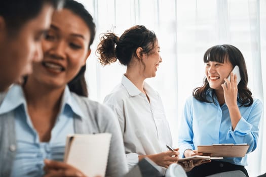 Asian office worker with smile working together in friendly corporate office environment. Group of happy business people in workplace with strong productive teamwork and sharing idea. Meticulous