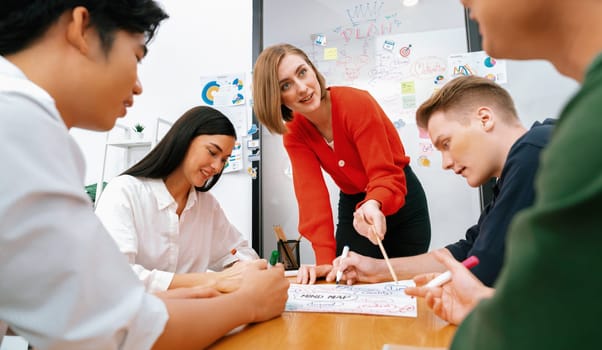 Creative happy business team brainstorming and sharing idea by using mind map and graphic graph while young beautiful project manager pointing at important point at business meeting. Immaculate.