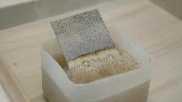 Chemical inspection of plate. Clip. Bubbling chemical liquid with metal plate. Chemical reaction with the factory part. Industrial Laboratory.