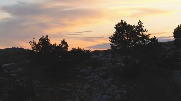 Top view of rocky top on background of sunset colors with clouds. Shot. Colorful picturesque landscape of sunset sky with clouds.