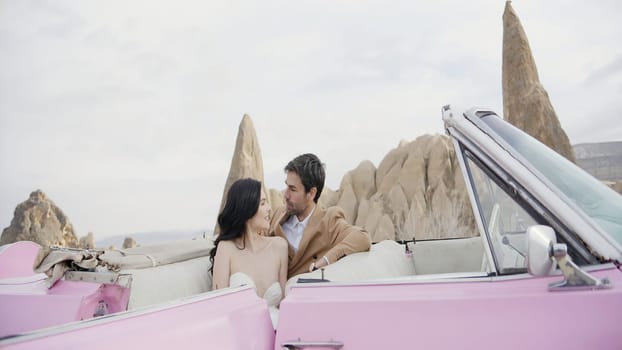 Elegant photo shoot of the newlyweds. Action.A beautiful slender girl in a white long dress with her man posing for the camera on the street next to the car and in a heated room with a bed. High quality 4k footage