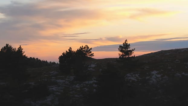 Top view of rocky top on background of sunset colors with clouds. Shot. Colorful picturesque landscape of sunset sky with clouds.