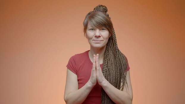 Woman greets with folded hands. Action. Yoga greeting with gratitude. Woman greets in Buddhist way on isolated background.