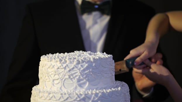 hands of bride and groom cut of a slice of a wedding cake. Bride and Groom at Wedding Reception Cutting the Wedding Cake. The bride and groom cut the wedding cake HD