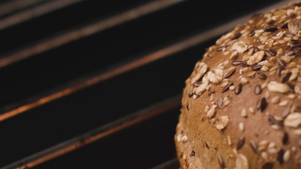 Close-up of hot Burger bun on grill. Stock footage. Delicious grain bread is grilled. Bun on grill for tasty Burger. Round loaf of bread to roast on fire.