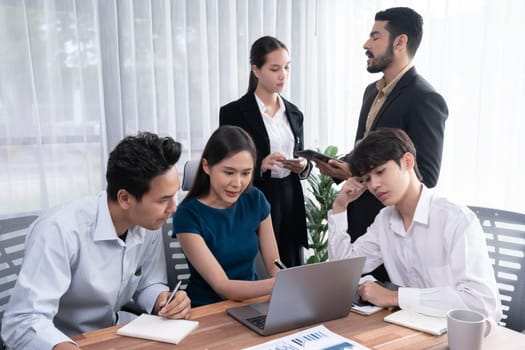 Professional Asian employee work together as team in corporate office, discussing business plans and data to achieve success on desk with laptop. Modern office worker teamwork concept. Concord