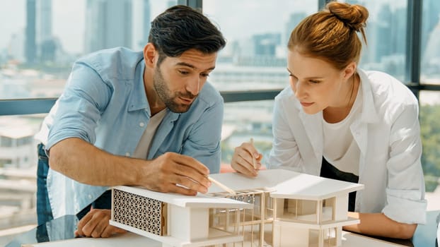 Cooperative architect engineer team working together to measure house model by using pencil. Successful caucasian interior designer team inspect architectural model construction. Design. Tracery